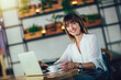 © Mediteraneo - Young woman sitting in cafeteria and using credit card for online shopping
