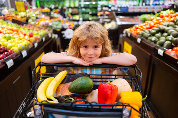 Wall Mural - Child shopping in supermarket. Healthy kids food. Child in supermarket buys vegetables.