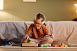 © Seventyfour - Portrait of young girl with down syndrome playing with toy blocks alone and wearing noise cancelling earphones, overstimulation concept, copy space