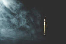 Assault rifle bullet in smoke on black background. Assault rifle bullet vintage background photo. War and death concept.