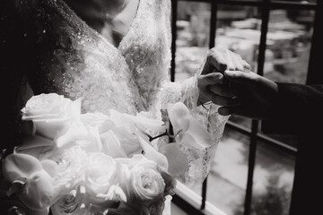 Wall Mural - The first meeting of the groom in a black suit and the bride in a white wedding dress with a bouquet in the interior of a photo studio, hotel, on black background