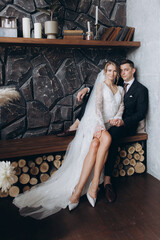 Wall Mural - The first meeting of the groom in a black suit and the bride in a white wedding dress with a bouquet in the interior of a photo studio, hotel, on black background