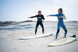 © Westend61 - Man teaching woman surfing lesson on beach
