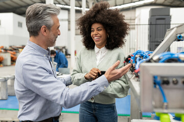 Smiling engineer discussing with technician in factory