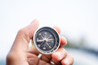 © TECHNOLOGY FACTORY - Man hand holding compass on city and car blurred background Using wallpaper or background travel or navigator image.