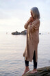 © Westend61 - Woman with eyes closed standing on rock at beach