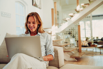 Caucasian female teen typing on laptop sitting on couch