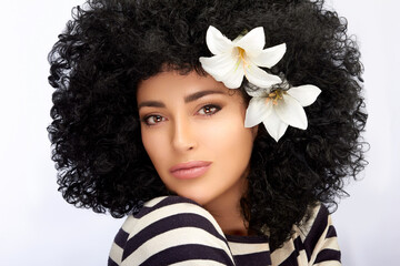 Wall Mural - Fashion Model girl with Healthy Curly Afro Hairstyle and Lily Flowers in Hair. Beauty portrait isolated on white with copy space