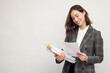 © Martin Villadsen - Smiling business woman with work in hands, standing isolated on white, looking happy about the papers she's reading and holding.