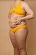 © Юля Бурмистрова - Cropped vertical photo overweight fat naked woman, obesity, excess fat in yellow swimsuit. Big size. Holding stomach flabs, visceral, cellulite. Self acceptance, body positive, plus size, friable skin