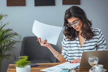 Worried and desperate woman banking and accounting home monthly and credit card expenses with computer laptop doing paperwork in living cost stress and paying bills problem.