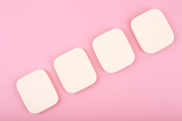 close up of four make up sponges in diagonal row on bright pink background