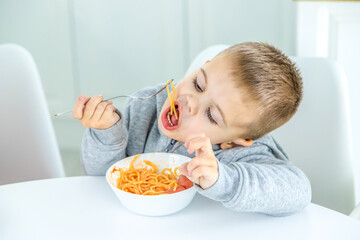 Wall Mural - children in the kitchen at the table turning pasta.