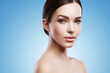© blackday - Young woman with natural makeup and smooth skin against light blue background