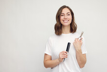 Young Brunette Woman Over Isolated White Background With Hairdresser Scissor And Comb. Looking Happy And Smiling. Ready For Haircut. Copy Space.