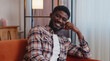 © Andrii Iemelianenko - Handsome candid happy casual calm young african american bearded man smiling friendly, glad expression, looking away dreaming resting, feel satisfied concept, sitting on sofa at home in living room