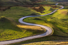 Winding curvy rural road leading through British countryside in The Peak District, UK.