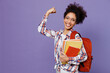 © ViDi Studio - Young girl woman of African American ethnicity teen student in shirt backpack hold books show muscles do winner gesture isolated on plain purple background. Education in high school college concept.