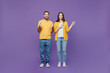 © ViDi Studio - Full body young couple two friends family man woman together in yellow casual clothes point index finger aside on workspace area mock up copy space isolated on plain violet background studio portrait.