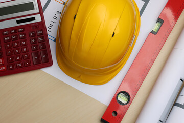 Wall Mural - Construction drawings, safety hat, calculator and bubble level on wooden table, flat lay