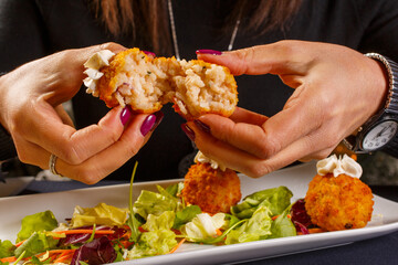 Arancino di riso fritto guarnito con un ciuffo di formaggio sopra e servito come antipasto in una pizzeria elegante