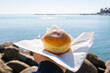 Brioche fritta ripiena di crema fotografata con il mare sullo sfondo