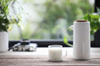 a glass cup of milk and pitcher pot and on wooden table in front of window