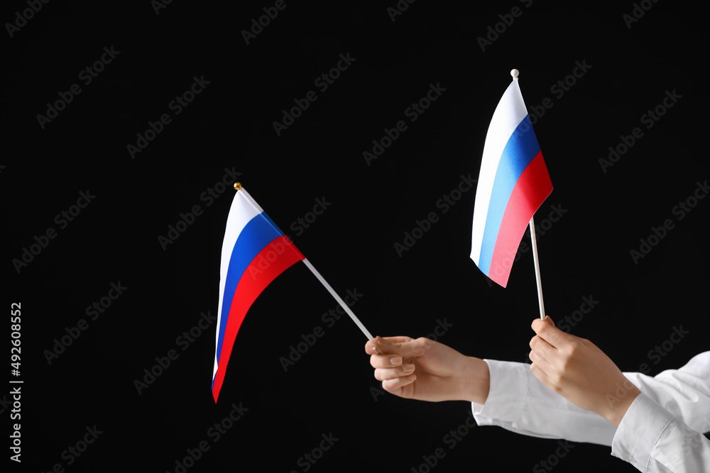 Woman holding Russian flags on dark background