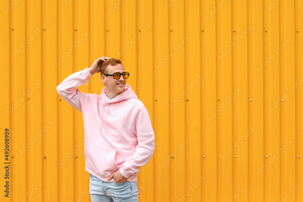 Young guy in stylish hoodie on color background
