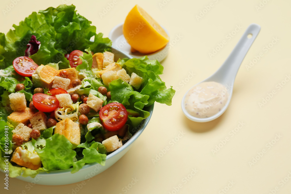Bowl with tasty vegan Caesar salad on beige background, closeup