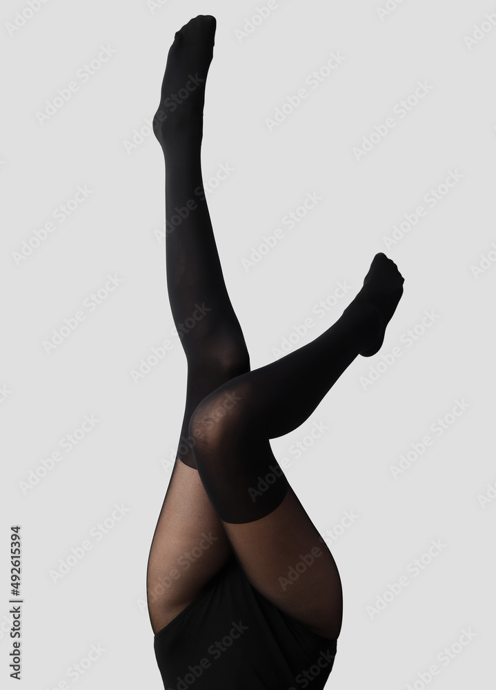 Beautiful young woman in black tights on light background