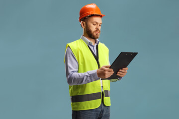 Wall Mural - Male engineer wearing a reflective vest and helmet holding a clipboard