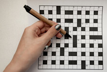 Female Hand Holds A Recycled Pen In Her Hands And Rejoices A Crossword Puzzle Top View Free Space
