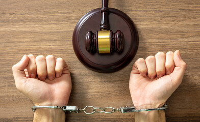 Handcuffed Convict. Court sentence Prison. Handcuff locked and judge gavel on table, top view..