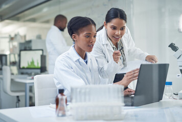 Improving lives one collaboration at a time. Shot of two young scientists using a laptop in a laboratory.