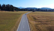 Luftaufnahme mit einer Drohne von einer Straße auf der ein Motorrad in Richtung Alpen fährt