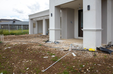 Wall Mural - The construction site of a large residential suburban house with dirt and construction rubbish debris scattered about. Concept of self-build home, new house, and unfinished landscaping project.