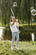© hetmanstock2 - Young mother holding her little daughter in a hands and blow a soap bubbles