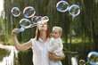 © hetmanstock2 - Young mother holding her little daughter in a hands and blow a soap bubbles