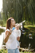 © hetmanstock2 - Young mother holding her little daughter in a hands and blow a soap bubbles