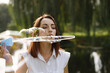 © hetmanstock2 - Woman blow a soap bubbles while standing in a park