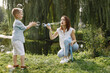 © hetmanstock2 - Young mother resting with her son in a park and blowing a soap bubbles