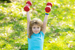 © Volodymyr - Healthy kids life and sport concept. Portrait of child boy working out with dumbbells outdoors. Motivation and sport concept for children. Funny excited child sportsman.