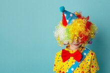 Funny Kid Clown Against Blue Background. Happy Child Playing With Festive Decor. 1 April Fool's Day Concept