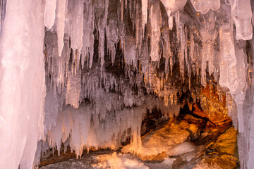 Wall Mural - Icicles in cave on Baikal lake at sunset