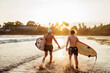 © Soloviova Liudmyla - Father with teenager son walking with surfboards by the sandy ocean beach with palm trees on background lightened with sunset sun. They enjoy summertime. Family active vacation concept.