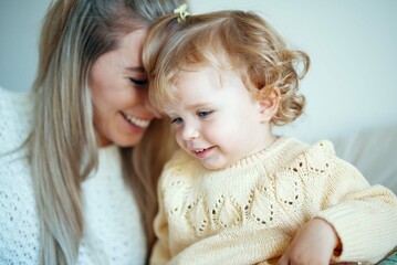 Young beautiful mother playing with baby daughter at home.