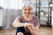 © Syda Productions - sport, fitness and healthy lifestyle concept - smiling senior woman with smart watch or tracker exercising at home