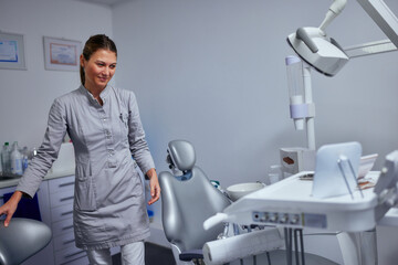 Wall Mural - Young female dentist standing in her dental office