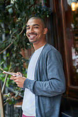 Aufkleber - Just texting a friend to meet up with me. Portrait of a young man texting on his cellphone outside.
